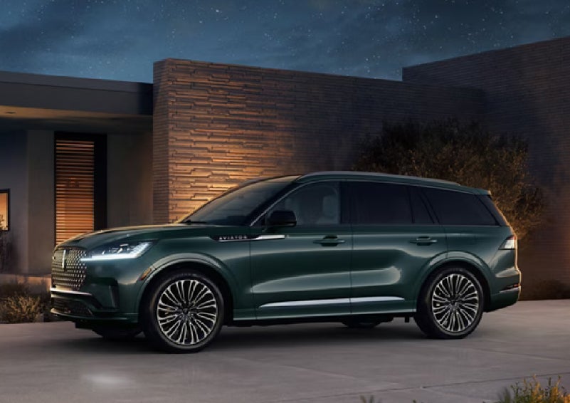 A green 2027 Lincoln Aviator® SUV is parked outside a contemporary home. | South Bay Lincoln in Hawthorne CA