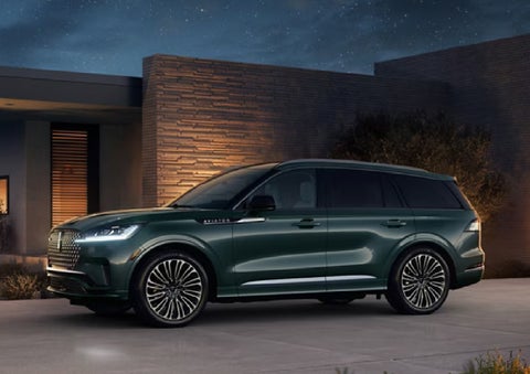 A green 2027 Lincoln Aviator® SUV is parked outside a contemporary home. | South Bay Lincoln in Hawthorne CA