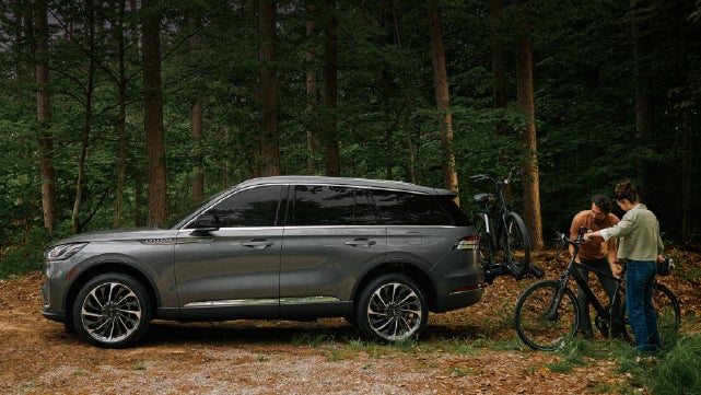 A father and son load e-bikes on a bike rack attached to a 2027 Lincoln Aviator® SUV. | South Bay Lincoln in Hawthorne CA