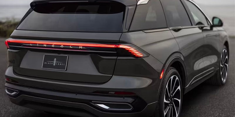 Rear-side view of the 2024 Lincoln Nautilus parked on the road, showcasing its full-width LED taillight strip and sculpted liftgate.
