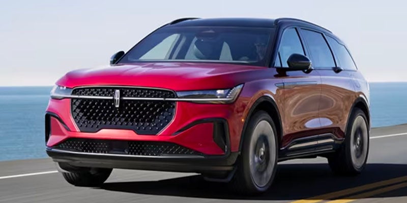 A 2024 Lincoln Nautilus gliding along a highway with the sea shimmering in the background.