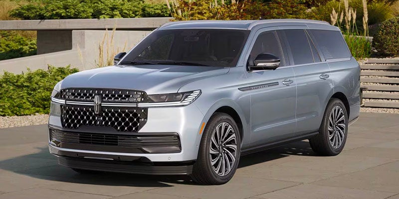 Front view of a 2025?Lincoln?Navigator parked beside a scenic road, surrounded by beautiful nature.